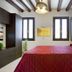 Margherita House Venice bedroom with red bedspread, exposed beams, and black-framed windows in Venice
