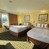 Super Inn By OYO Daytona Beach Near Airport room with two beds, window light, and framed wall art