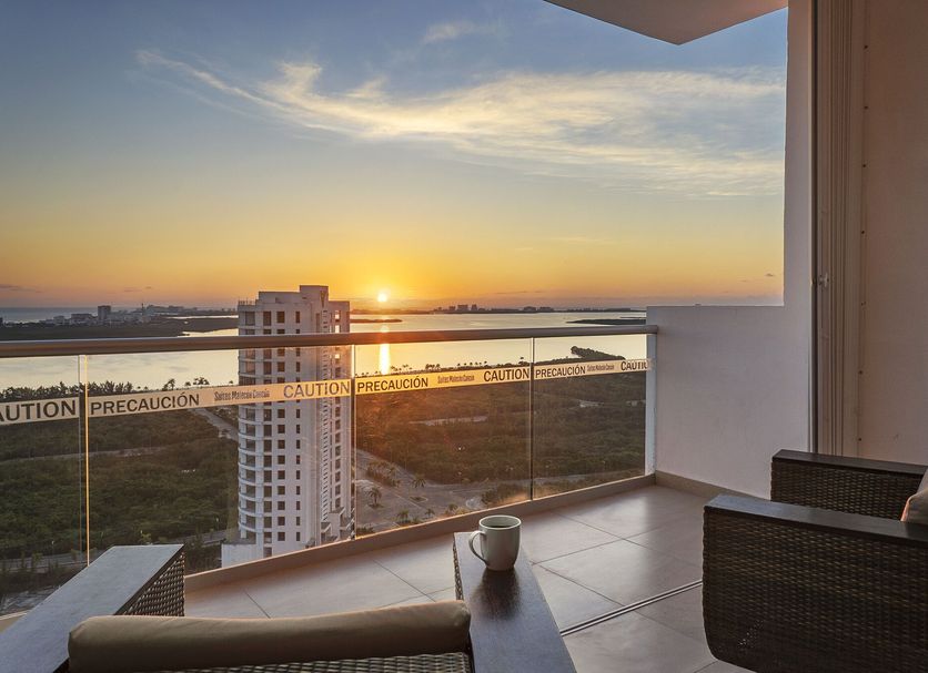 Suites Malecon Cancun balcony with sunset view over Cancún and distant water