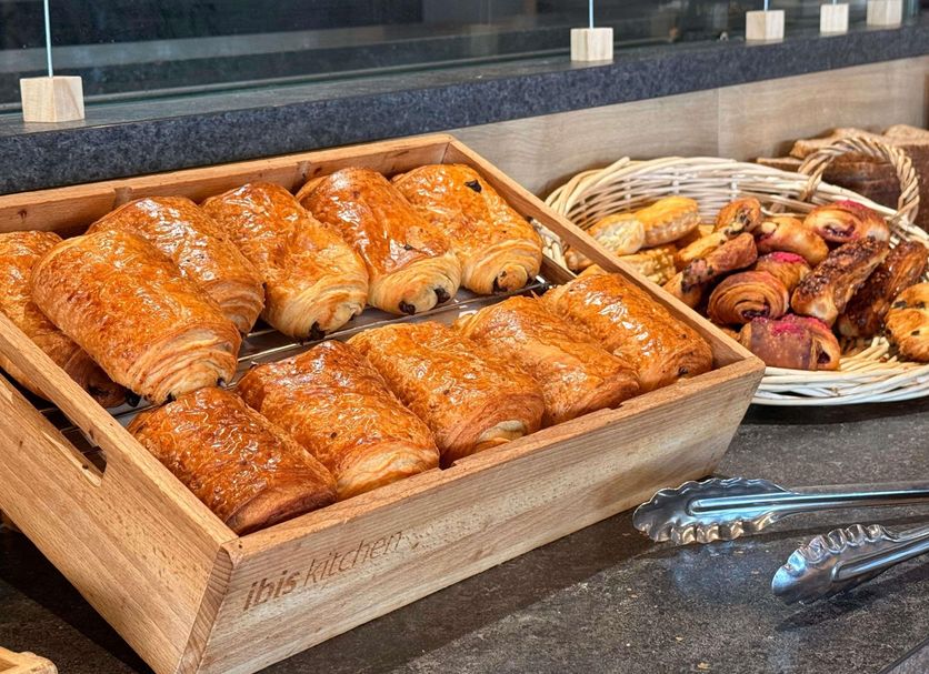 Ibis Dijon Sud breakfast buffet with croissants and pastries in a wooden tray, Dijon