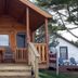 The Beach House in Mackinaw City: small wooden cabin with front porch, steps, chairs, and table