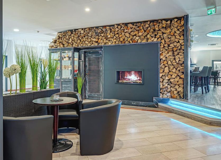 Hotel Stadt Mühlhausen lounge with fireplace seating and stacked wood wall, Mühlhausen