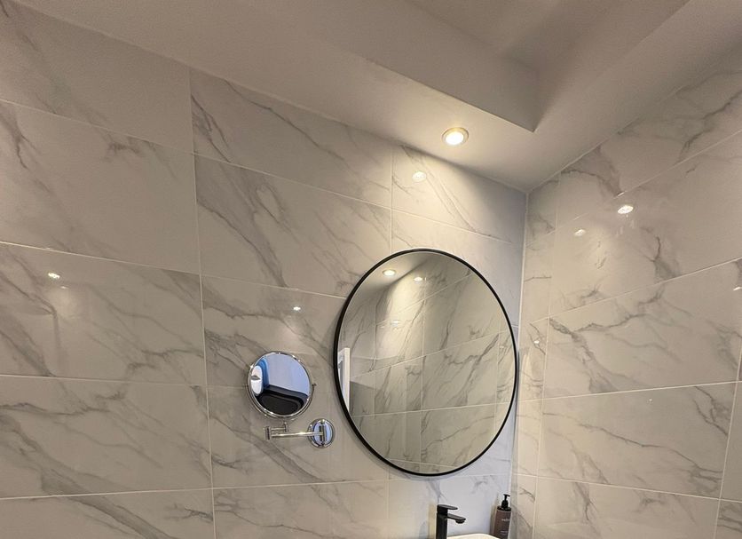 Muthu Oban Hotel, Oban bathroom with round mirror, vessel sink, toilet and marble-look tile walls