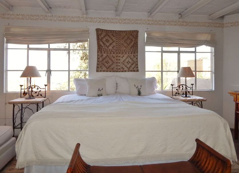 Suites Santo Domingo in San Miguel de Allende bedroom with king bed, windows, and bedside lamps