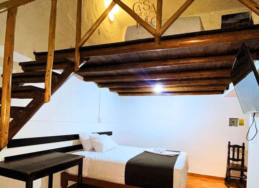 La casa de theo in Arequipa: loft-style room with wooden mezzanine, bed, and staircase