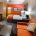 Best Western Executive Inn El Campo room with orange accent wall, sofa, desk, TV and two beds