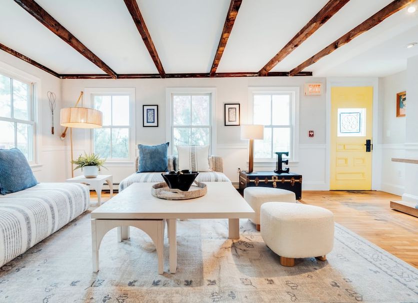 Ellery Hotel Provincetown living room with wood beam ceiling, sofas, coffee table and yellow door