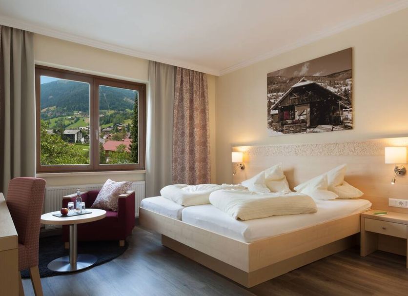 Family & Sporthotel Kärntnerhof room with double bed, mountain view, and seating area in Bad Kleinkirchheim