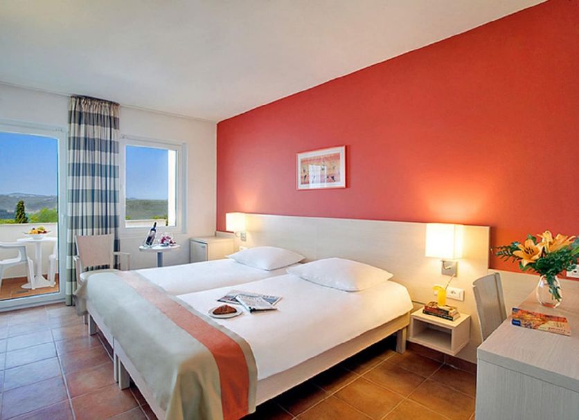Valamar Tamaris Resort in Vabriga guest room with balcony sea view, double bed, and red accent wall