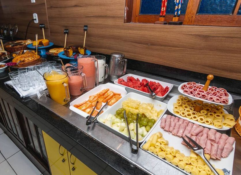Hotel Gogó da Ema in Maceió buffet table with juices, pastries, fruit, cold cuts and sliced bread