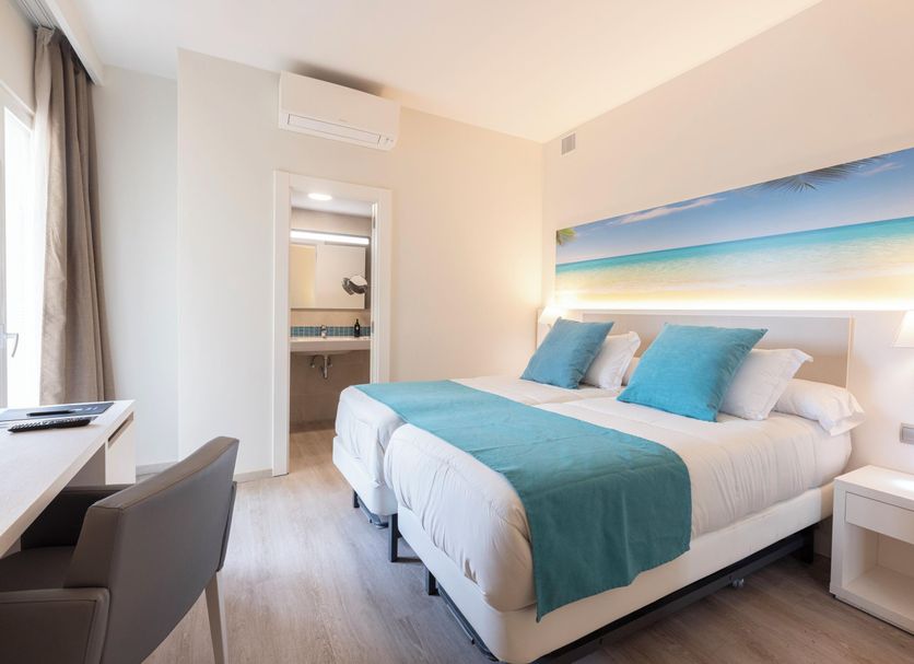 Invisa Hotel Es Pla - Adults Only room in Sant Antoni de Portmany with bed, desk and beach artwork