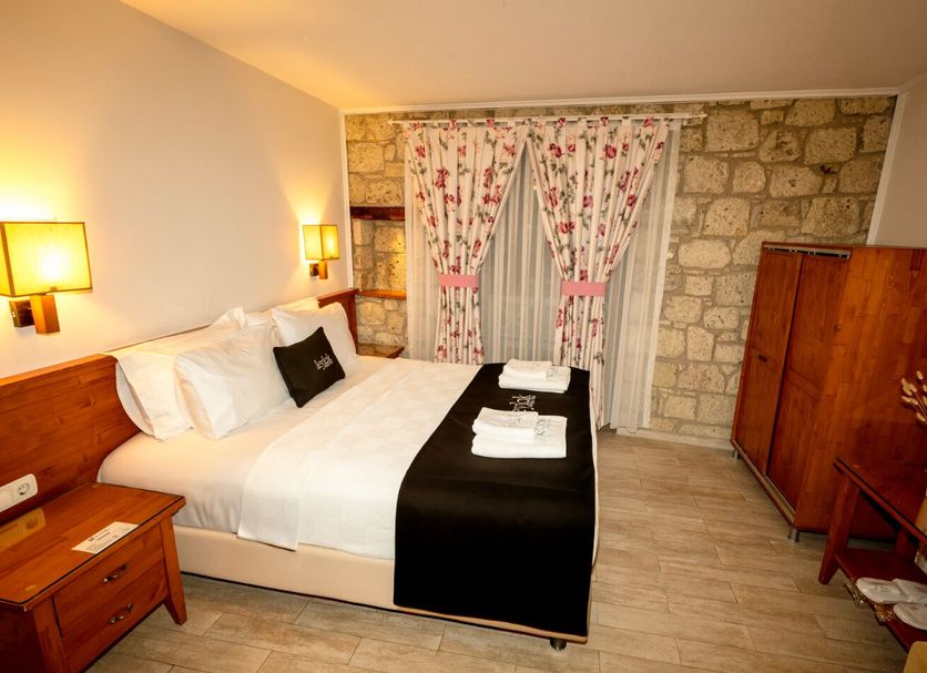 Alacati Leylak Hotel in Alacati guest room with stone wall, floral curtains, and double bed