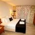 Alacati Leylak Hotel in Alacati guest room with stone wall, floral curtains, and double bed