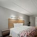 Red Roof Inn Greensboro Airport guest room with king bed, desk, and wood flooring in Greensboro.
