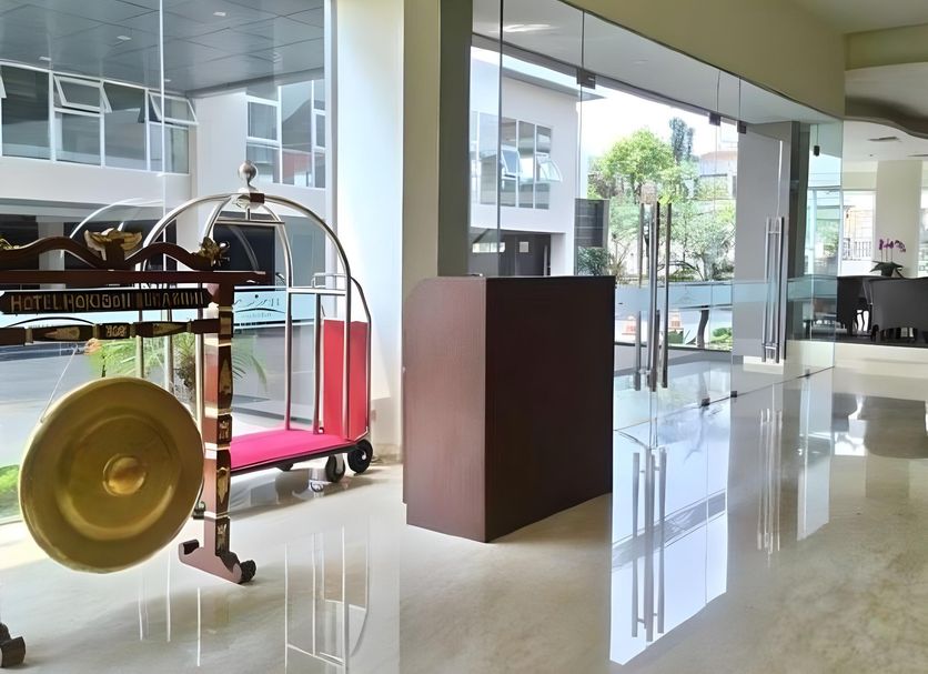 Horison Hotel Sukabumi lobby with bell cart, glass entry doors, and poolside view