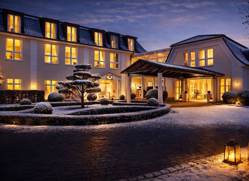 Hotel Sonne in Rheda Wiedenbrueck exterior at dusk with lit windows, entrance canopy and lanterns