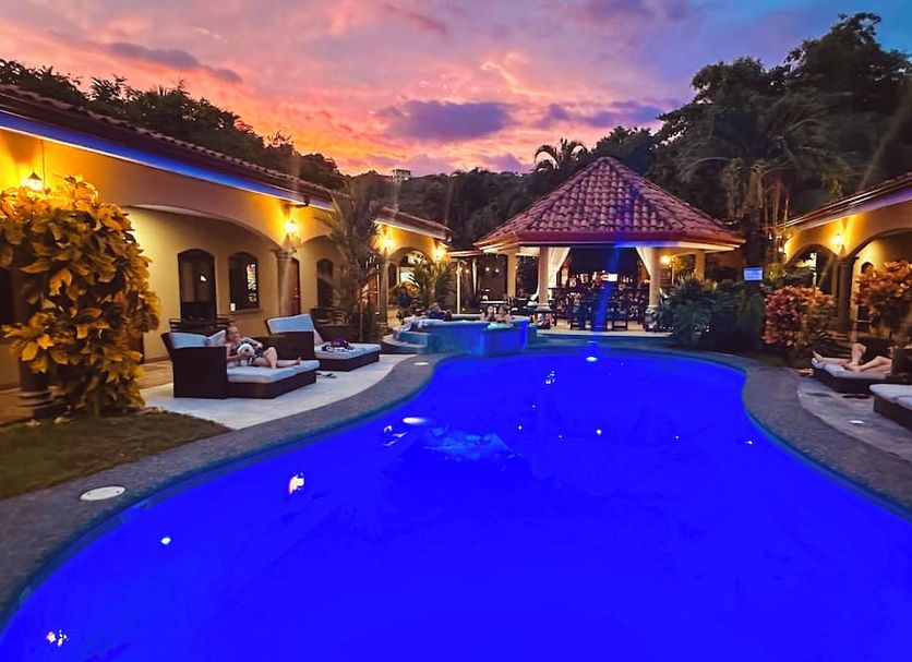 Las Brisas Resort and Villas in Jacó, pool courtyard at sunset with lounge chairs and gazebo
