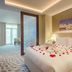 Riviera Rayhaan by Rotana Doha guest room with rose-petal bed decor and seating area