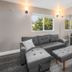The Inn at Boatworks, Lake Tahoe in Tahoe City: gray sectional sofa, ottoman, and window view of trees