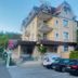 Hotel De La Paix in Interlaken, 3-star hotel exterior with parked cars and mountain backdrop