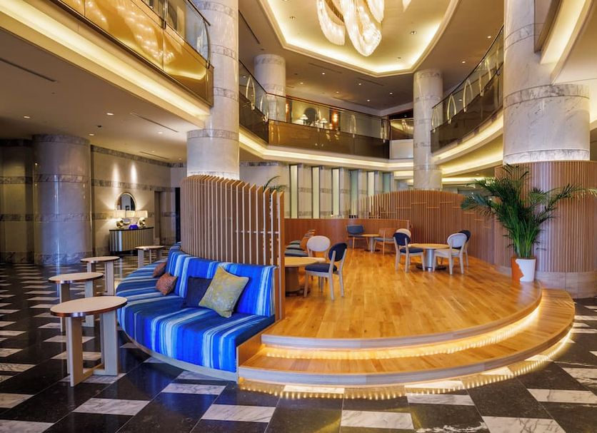 JR Hotel Clement Takamatsu lobby with curved stage seating, warm wood floors and modern chandelier