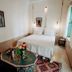 Riad Dar Ayur Marrakech guest room with king bed, patterned table, armchairs, and tall window