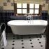 The White House in Bishop's Stortford bathroom with a clawfoot bathtub by a window and tiled floor