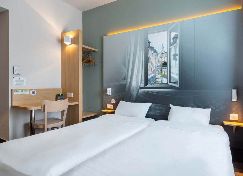B&B HOTEL Chartres Océane guest room with double bed, desk, and city-view wall mural in Chartres