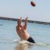 Tawas Bay Beach Resort in East Tawas: man jumping in shallow water to catch a football