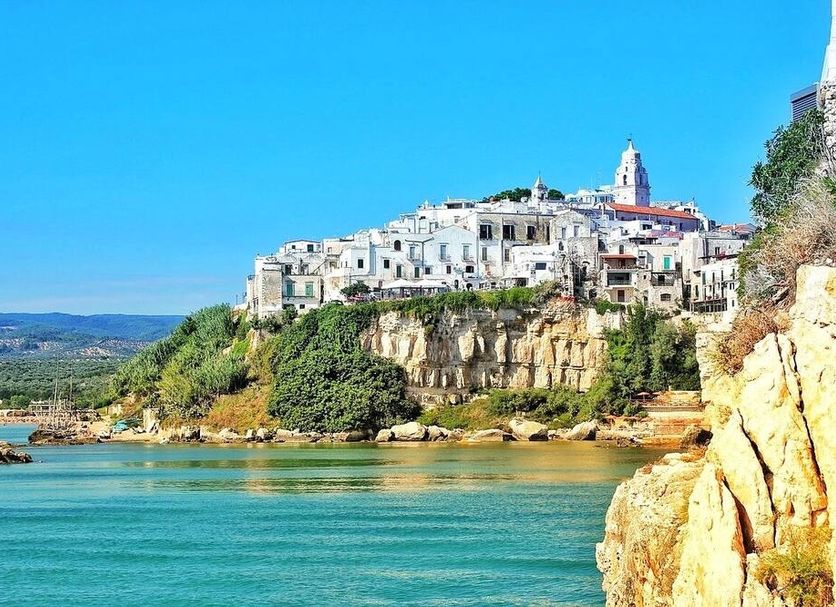 Al Castello Relais in Vieste with cliffside white buildings above a turquoise sea and rocky coast