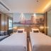 Zhongshan Tegao Business Hotel in Zhongshan room with two twin beds, sofa, and cityscape wall mural