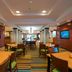 Fairfield Inn & Suites by Marriott Greenwood dining area with tables, chairs, and wall-mounted TVs