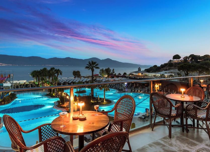 Liberty Kusadasi in Kusadasi with illuminated pools, terrace seating, and sea view at sunset