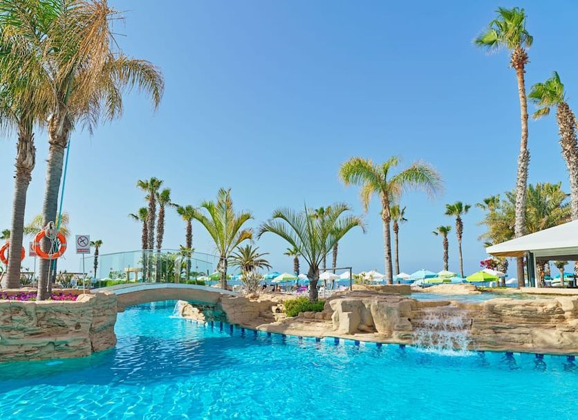 Leonardo Cypria Bay, Paphos: tropical pool area with stone bridge, palm trees and sea view