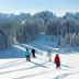 Skiers on snowy slopes near Chalet Hotel Régina in Les Gets, with forested mountains in the background