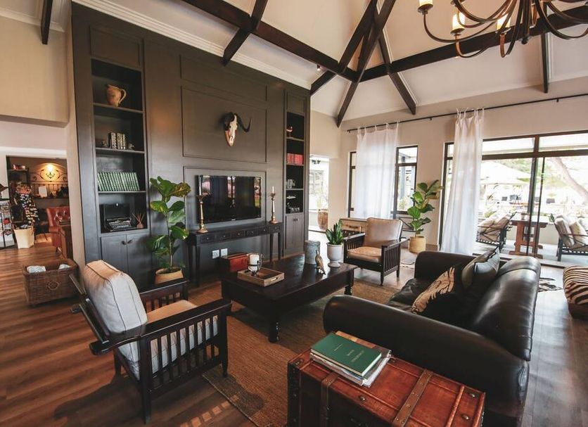Otjiwa Safari Lodge lounge with leather seating, fireplace, and large glass doors to a patio in Otjiwarongo