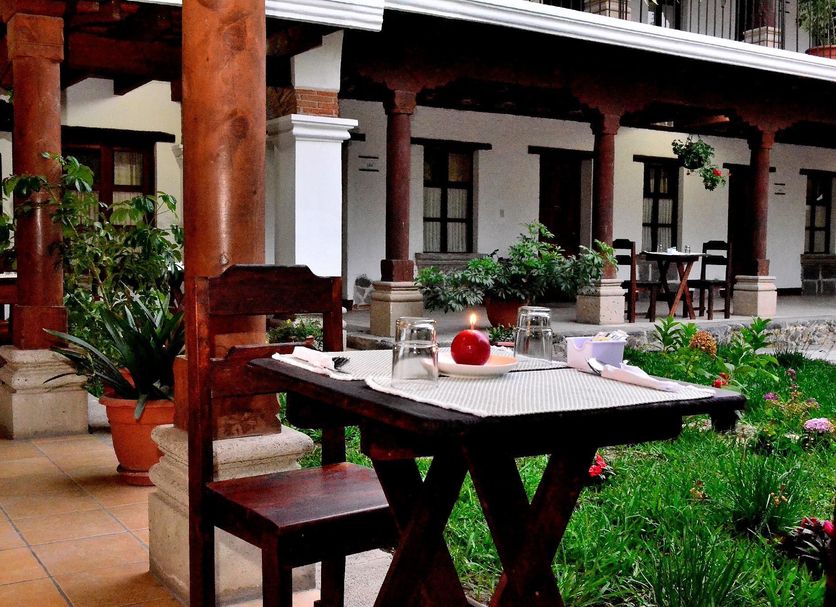 La Ermita de Santa Lucia in Antigua courtyard with table, chairs, greenery and colonial-style columns