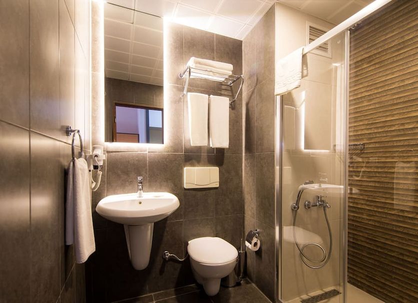 Club Hotel Sunbel bathroom with wall-mounted sink, toilet, shower and glass shower enclosure in Göynük