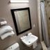 The 409 Bolivar Beach Hotel bathroom with sink, mirror, towels and tiled shower in Bolivar Peninsula