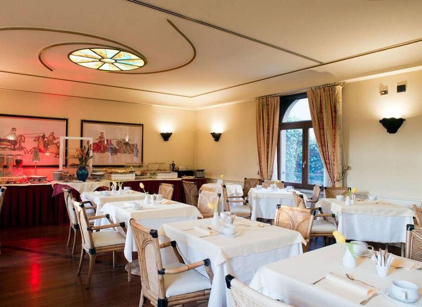 Hotel Milano Regency in Milan dining room with set tables, chandeliers, and arched window
