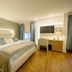Hotel-Residence Klosterpforte in Marienfeld guest room with king bed, desk, wall-mounted TV and wood floors