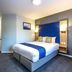 Days Inn by Wyndham London Stansted Airport guest room with double bed, blue accents, and seating area in Bishop's Stortford