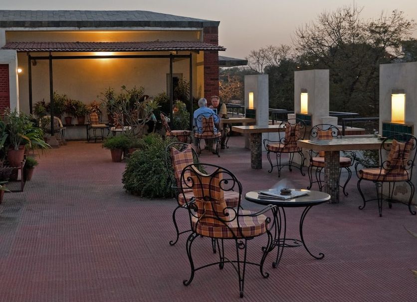 Atithi Guest House Jaipur terrace seating area with tables, chairs, plants and evening lighting