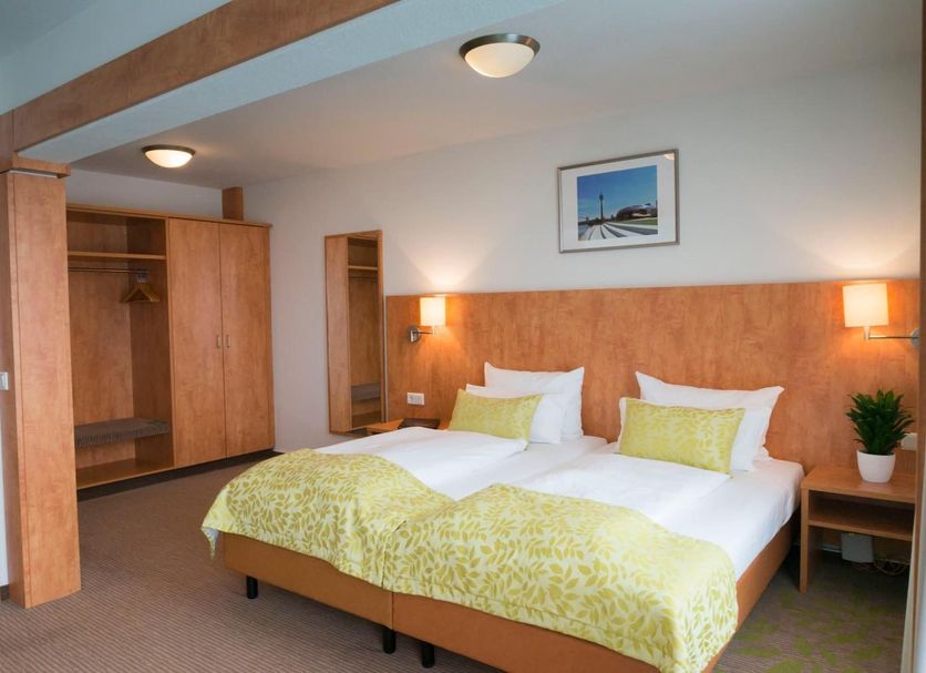 Hotel Mingarden Düsseldorf guest room with twin beds, wood accents, built-in closet and bedside lamps