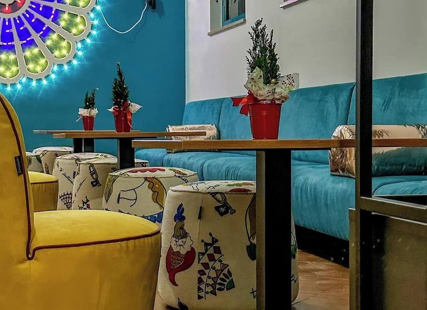 Il Crusco in Matera lounge with turquoise sofa, patterned stools and colorful wall decor