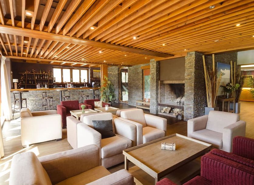 Reserva del Saja Hotel & Spa lounge with armchairs, stone fireplace and wood-slat ceiling in Renedo de Cabuérniga