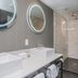 Sandman Signature Ottawa Airport Hotel bathroom with double sinks, mirrors and glass shower in Ottawa