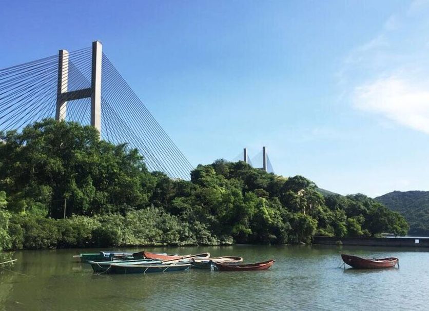 Solar Villas, Hong Kong: scenic harbor view with bridge, lush hills, and boats on the water
