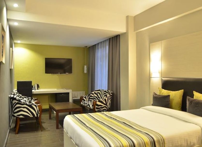 Cloud Hotel & Suites Nairobi guest room with king bed, work desk, wall TV and lounge chairs