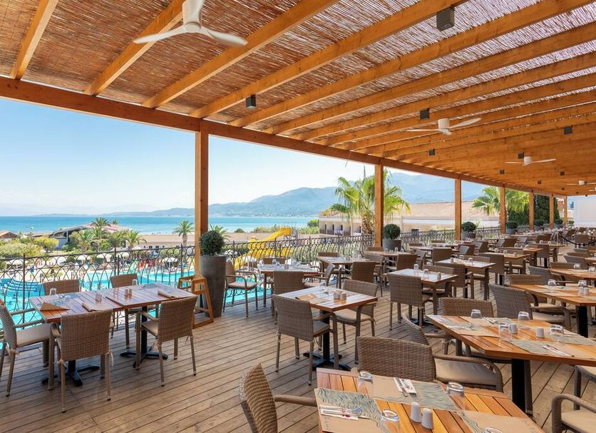 Roda Beach Resort & Spa in Roda with a shaded terrace dining area overlooking the pool and sea